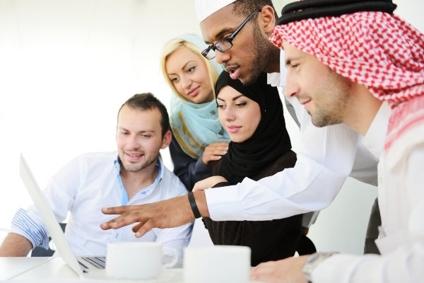 people in mideastern dress looking at laptop