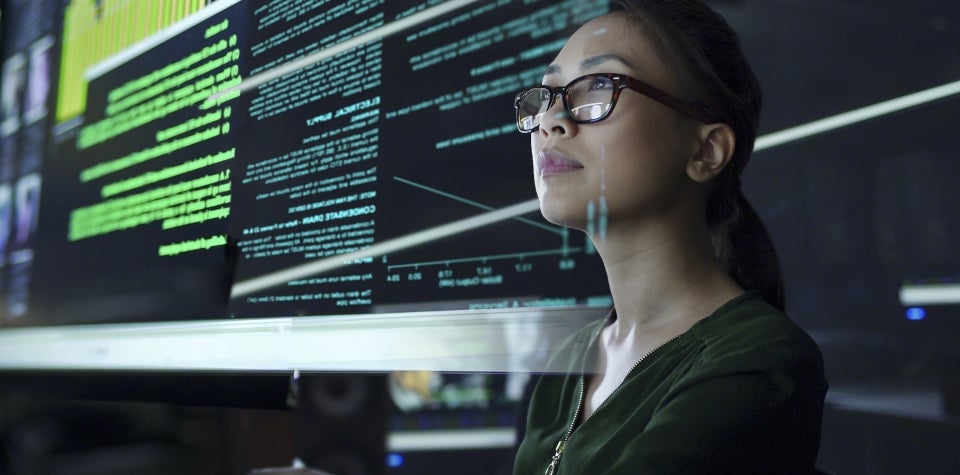 A woman looks at data on screens in front of her