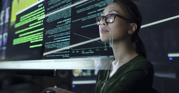 A woman looks at data on screens in front of her