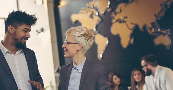 Image of executives smiling and talking in front of a map of the world.