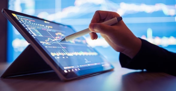 A hand interacts with an ipad displaying data