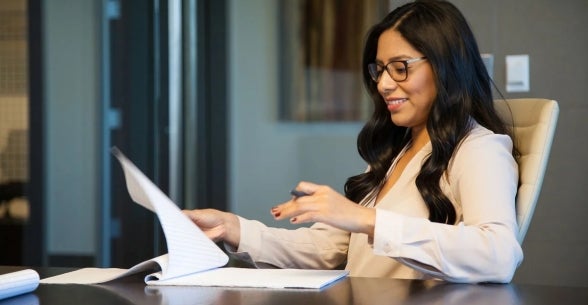 Image of a business woman in a conference room reviewing notes.