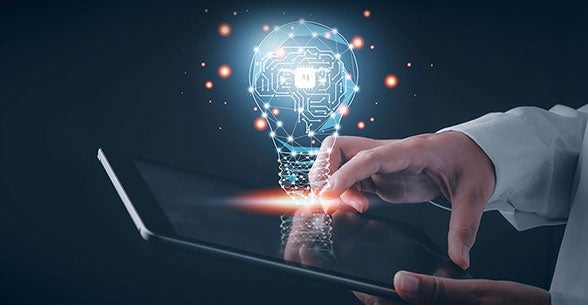 Artificial Intelligence - Fingers on a laptop keyboard with an idea cloud in the shape of a lightbulb.