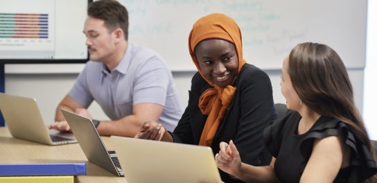 Image of diverse Thunderbird students talking with each other at a meeting