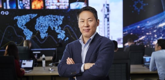 Image of an Executive Master Degree student in a suit standing and smiling in Thunderbird School of Global Management's Global Headquarters.