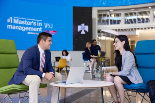 Image of Thunderbird students talking at a table in the Global Forum.