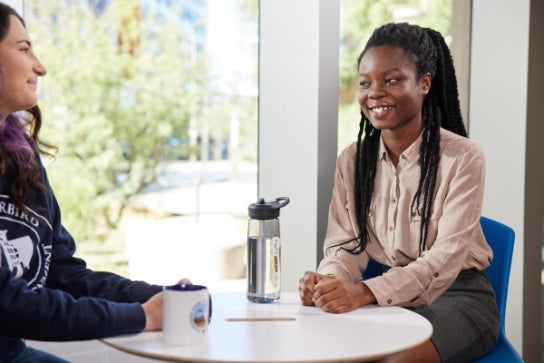 Two Thunderbird students having a conversation over coffee