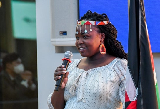 Image of a student speaker at Thunderbird Foundations holding a flag in the Global Forum